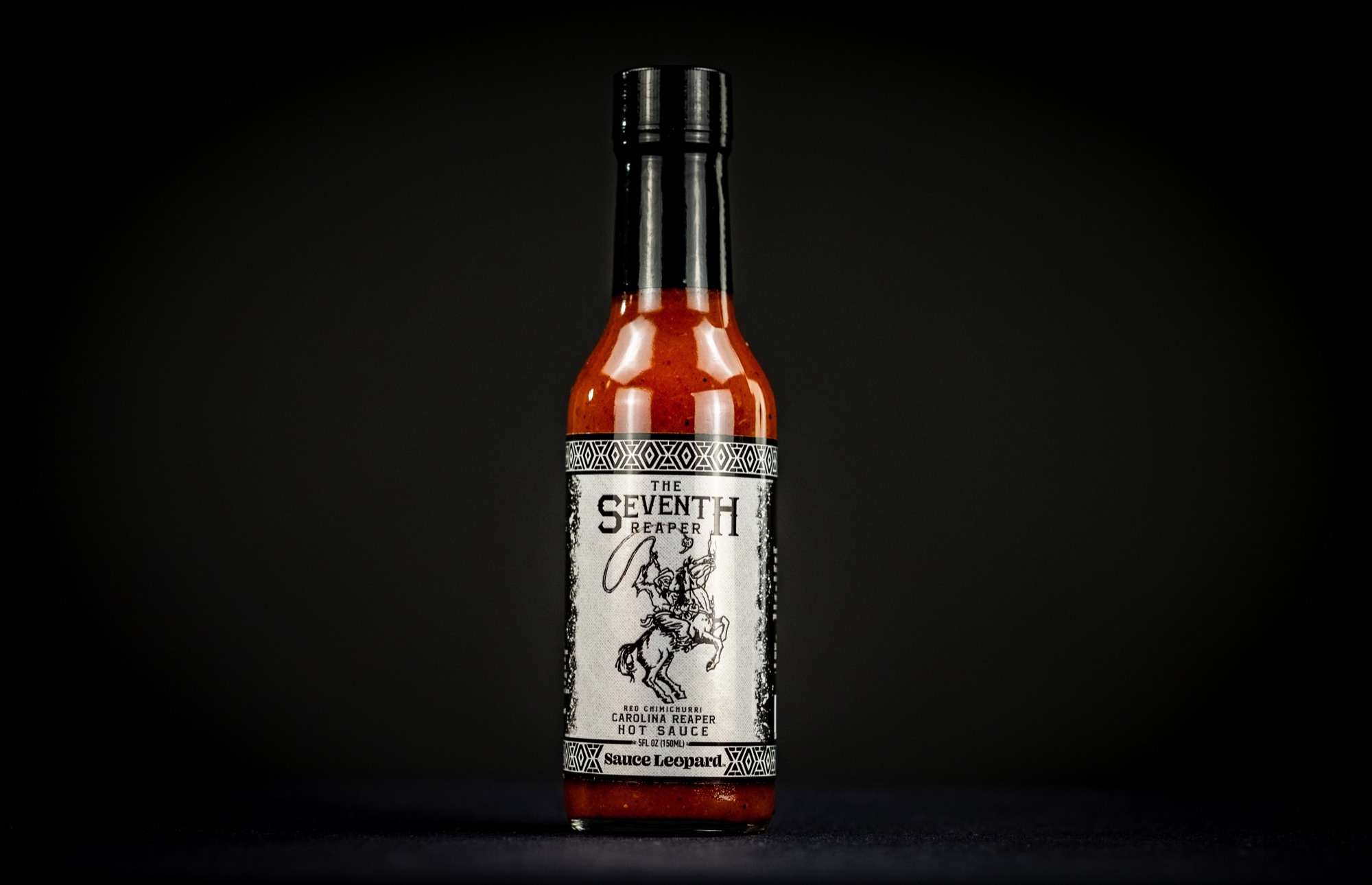 The Seventh Reaper sauce bottle photographed with peppers and fire